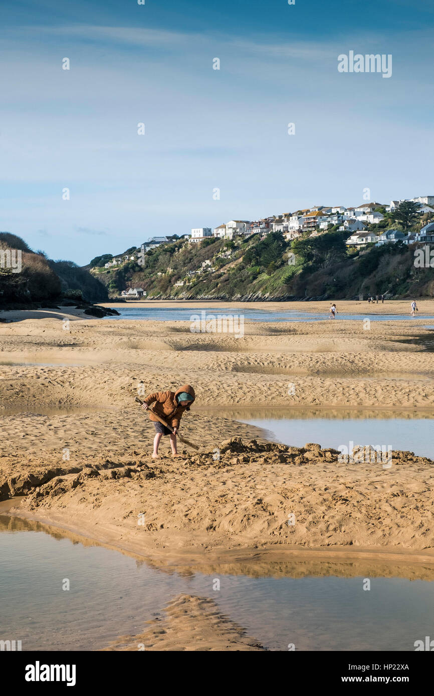 A young boy digging in the sand at low tide on the Gannel Estuary. Newquay, Cornwall, UK. Stock Photo