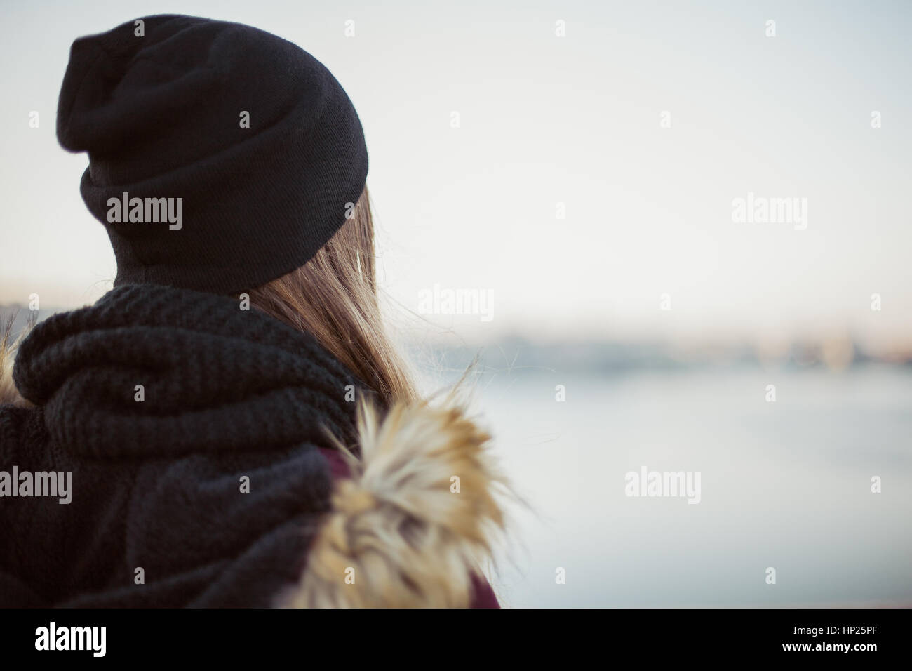 Back view of a sad hipster girl against blurred winter background Stock Photo