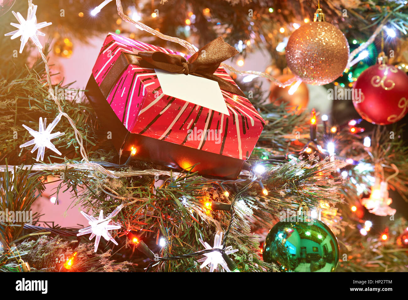gift laying on christmas tree with decorations on background Stock Photo