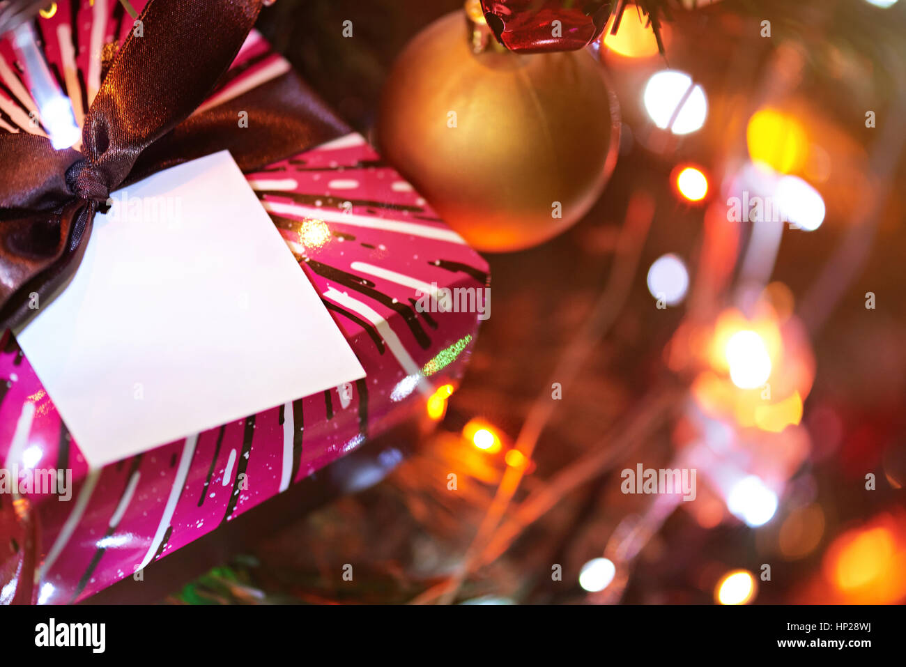 christmas brown gift box in glitter lights . Present for new year on christmas tree Stock Photo