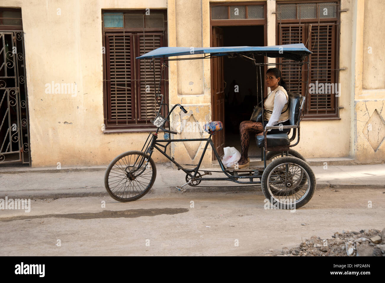 A Cuban woman sitting in the back of a bicycle taxi in the back streets of Havana Centro Cuba Stock Photo