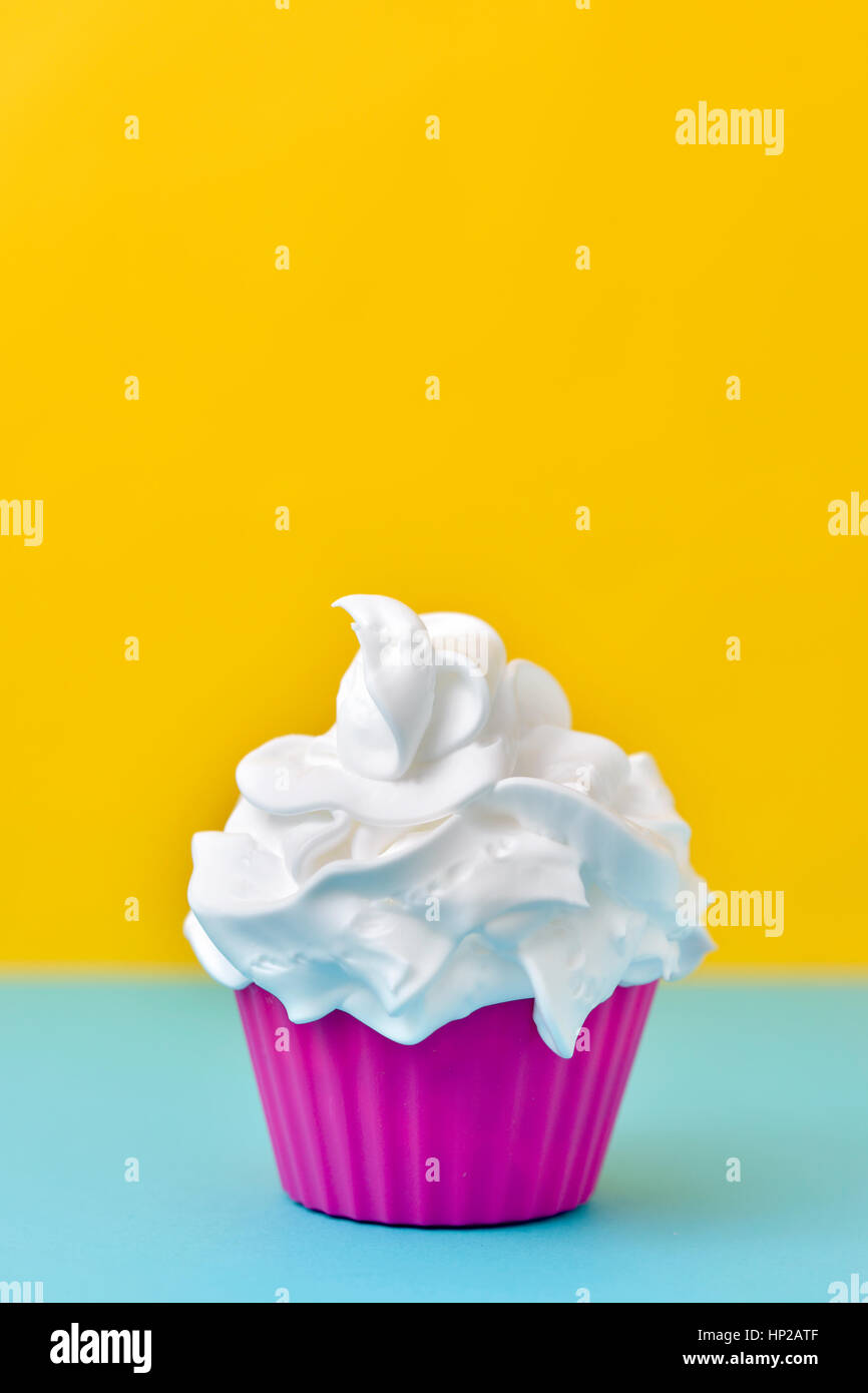 closeup of a pink plastic cup full of a white ice cream on a blue and yellow background Stock Photo
