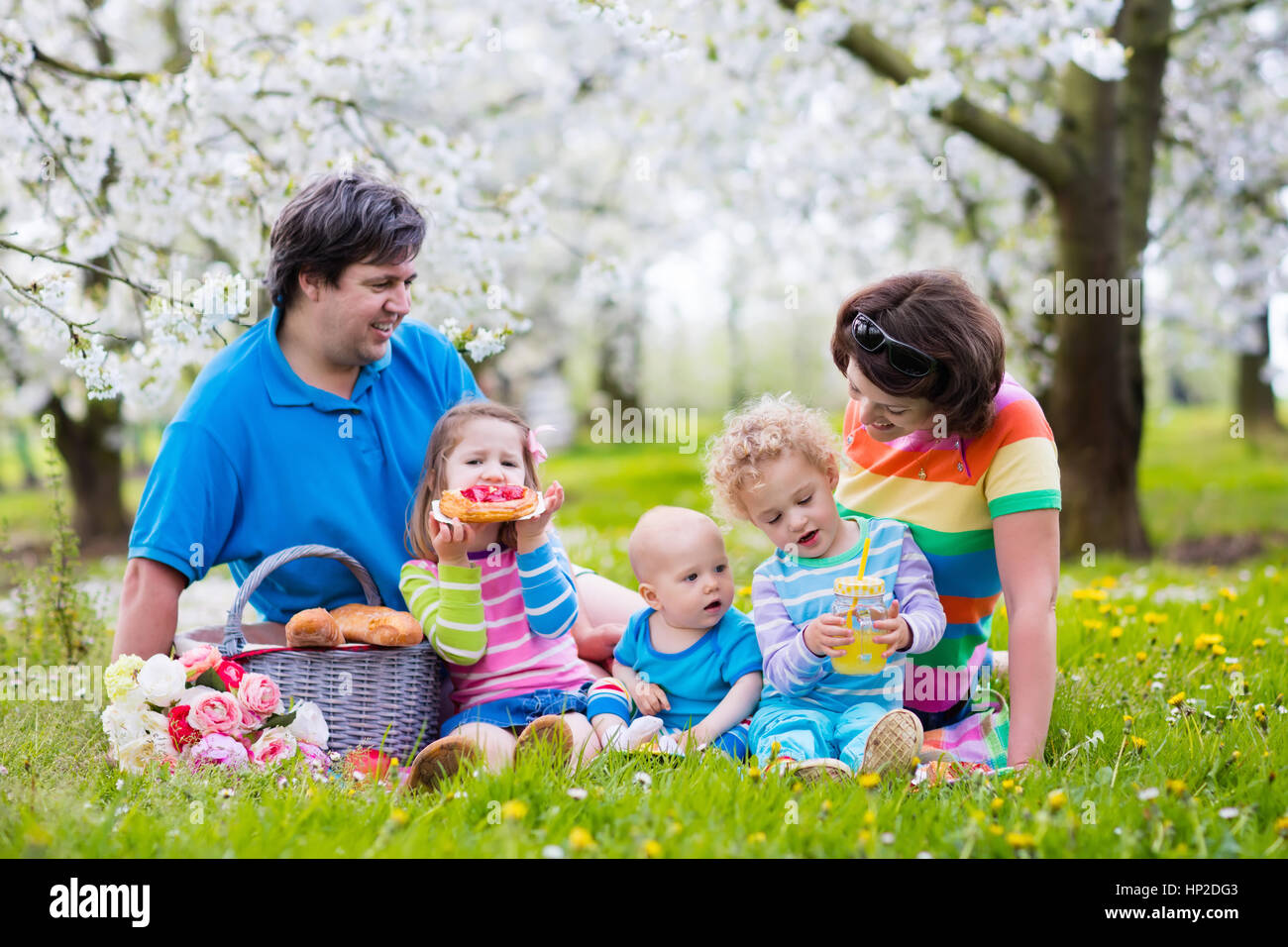 Big family with three little children eating lunch outdoors. Parents