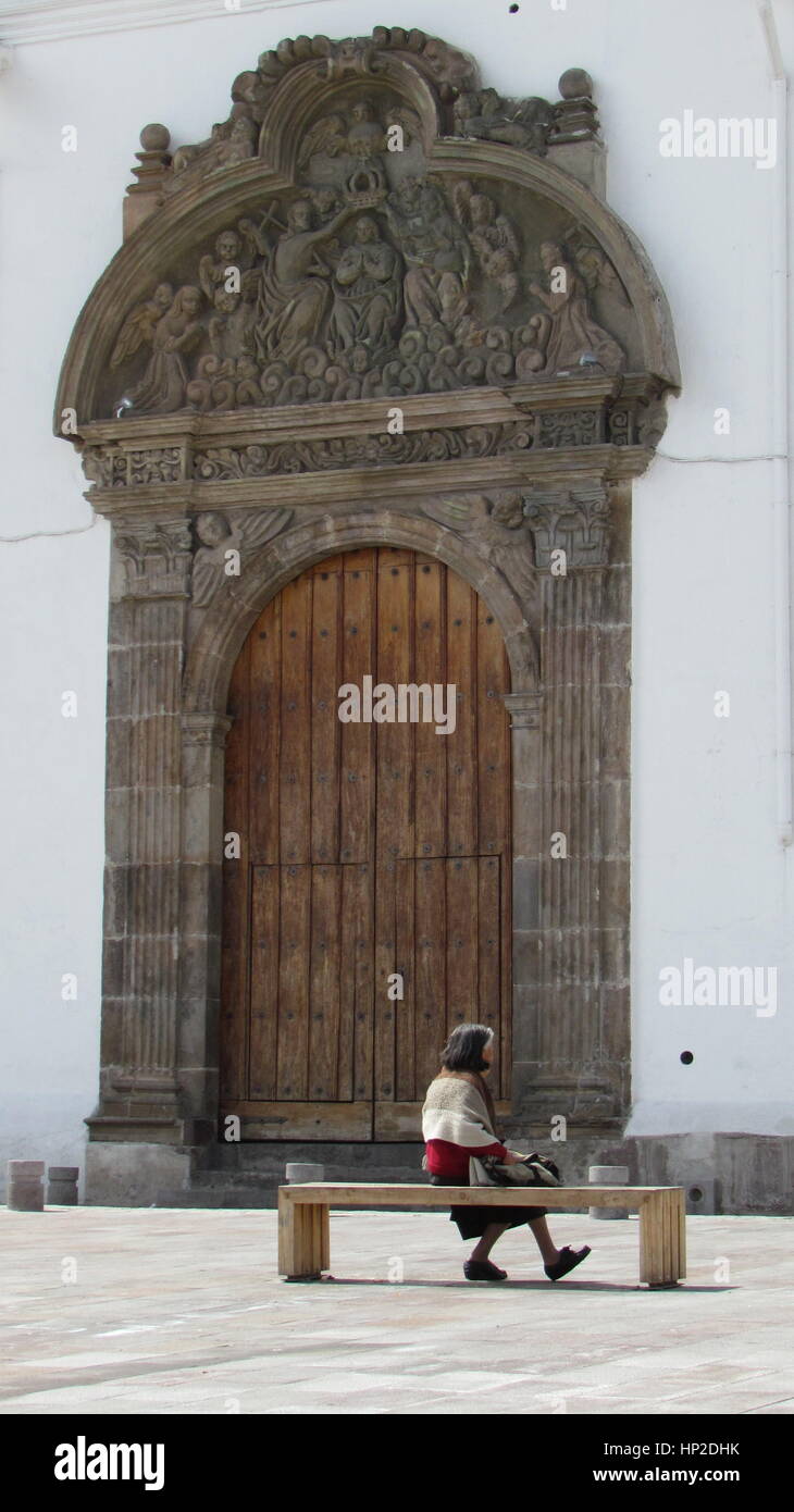Woman sitting on a bench in front of a Cathedral in Quito, Ecuador Stock Photo