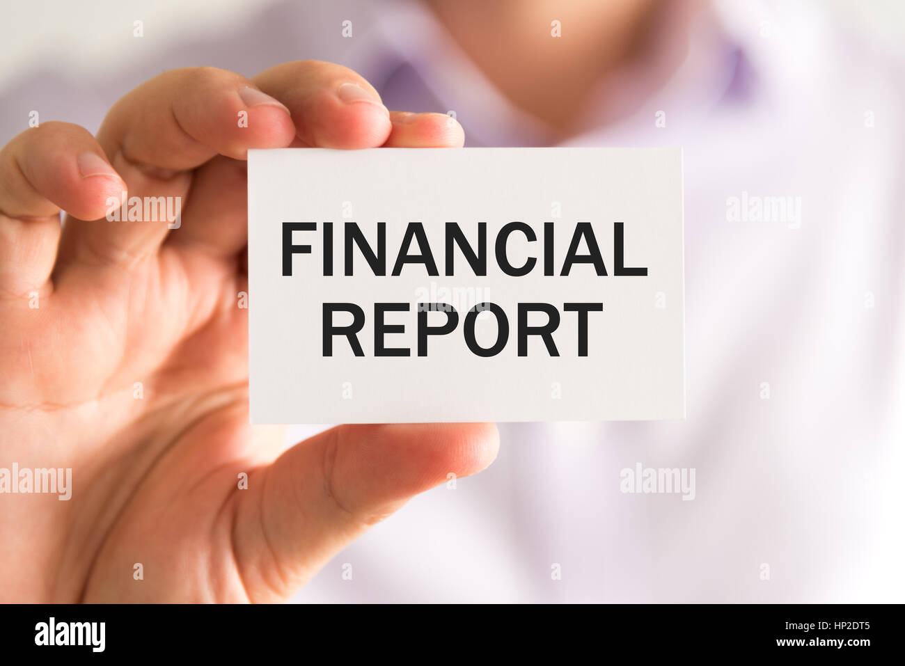 Closeup on businessman holding a card with text FINANCIAL REPORT, business concept image with soft focus background Stock Photo