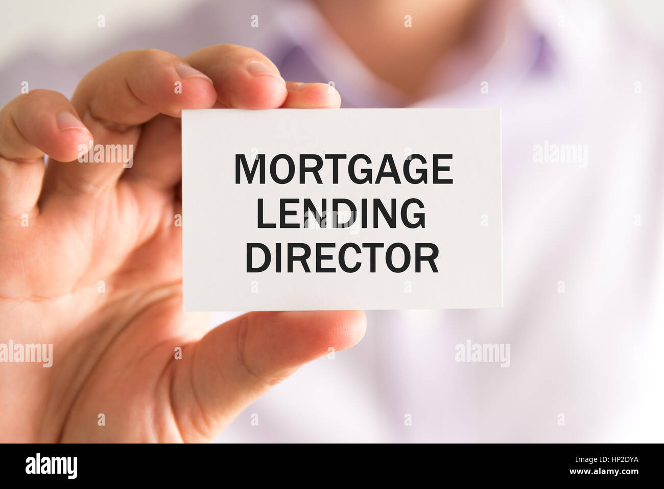 Closeup on businessman holding a card with text MORTGAGE LENDING DIRECTOR, business concept image with soft focus background Stock Photo