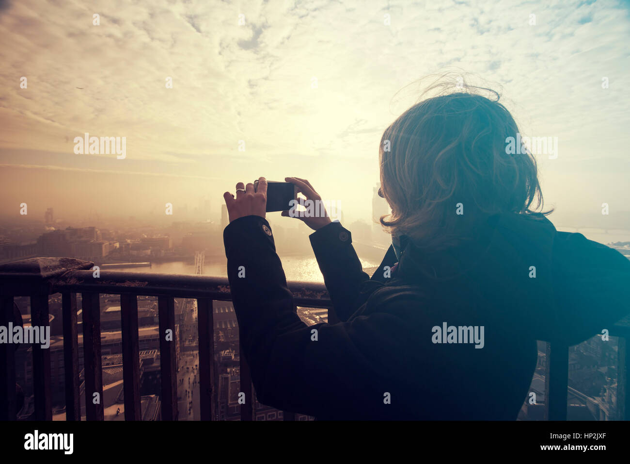 Young woman taking photos from the rooftop of St Paul's Cathedral on a foggy day in London, UK - city break - tourism concept Stock Photo