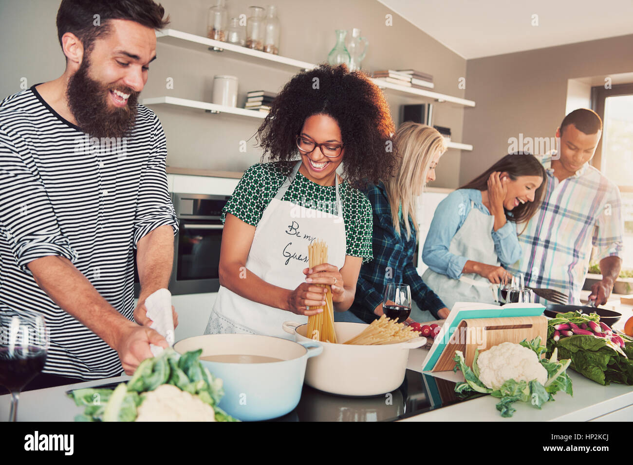 Five friends cooking at kitchen, having a lot of fun Stock Photo