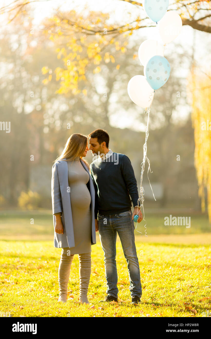 Young pregnant woman and man posing in autumn park with balloons in ...
