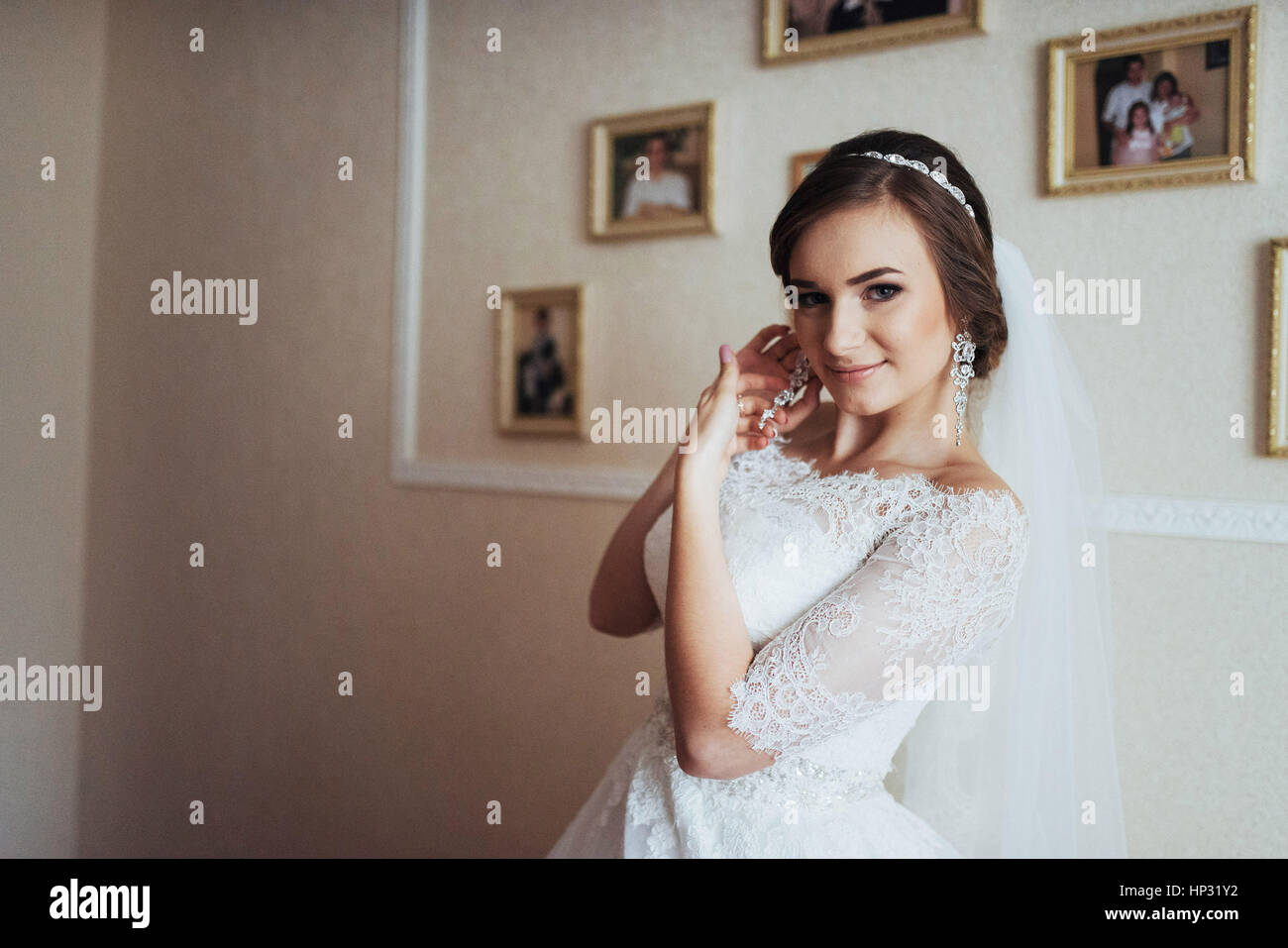 Wedding day. Beautiful bride trying on earrings Stock Photo