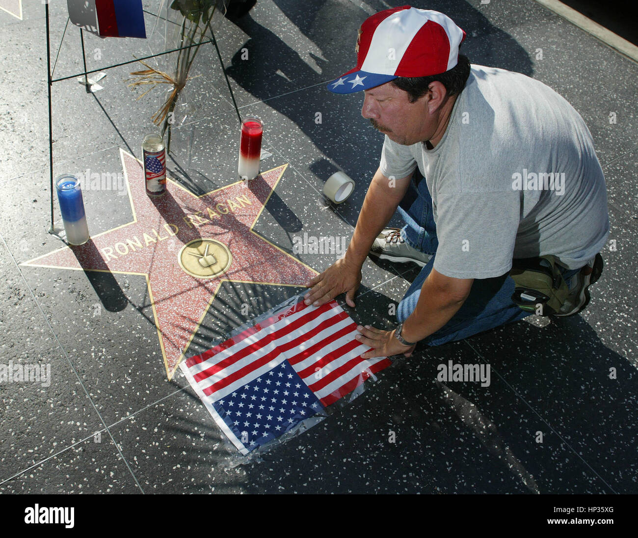 Rolando Gil Ocampo tapes a United States flag at a make shift memorial at  the Hollywood Walk of Fame star for the late President Ronald Reagan in Los  Angeles, California on June