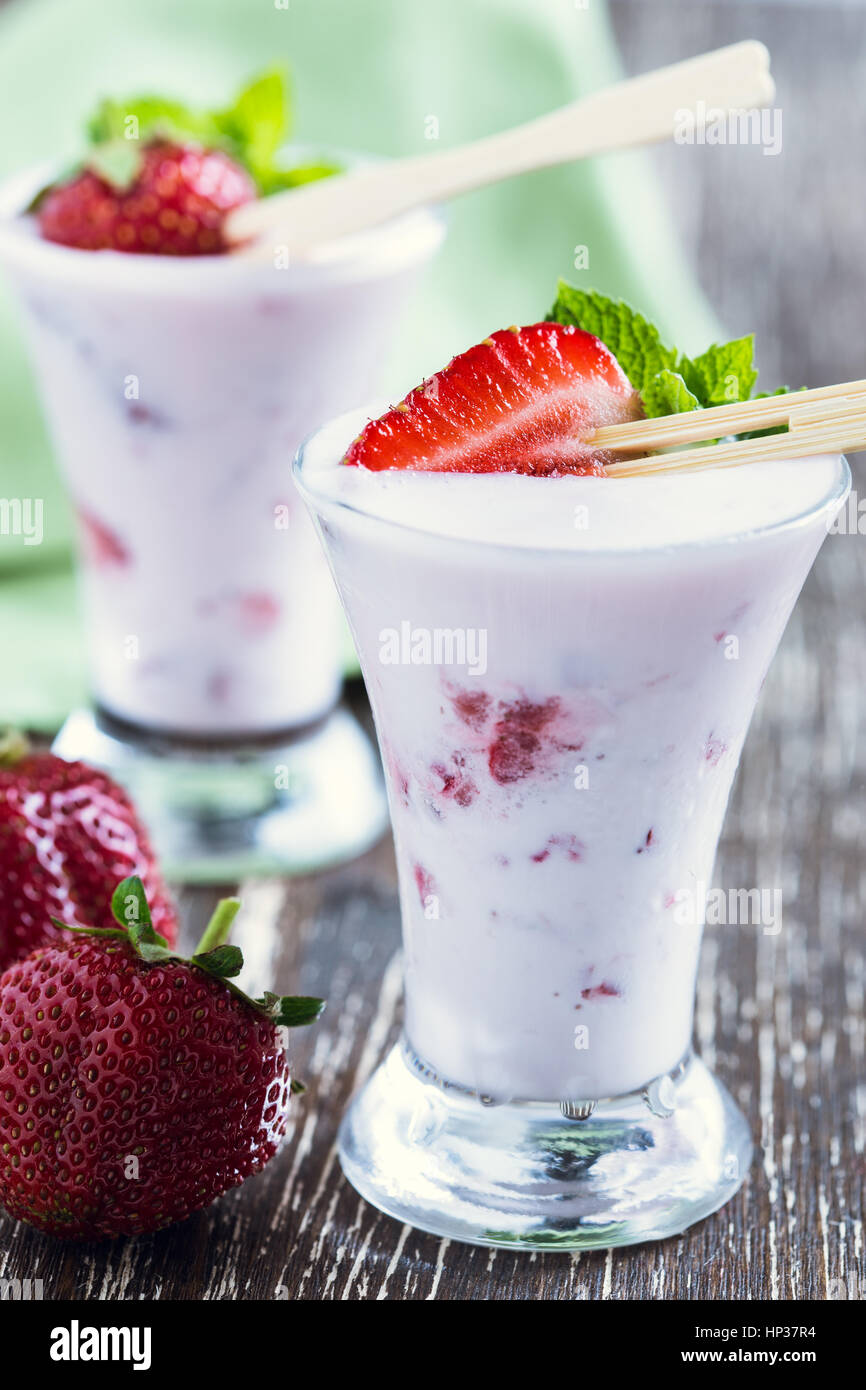 Frozen fruit smoothies with fresh strawberries on top served in chilled tall glasses, summer