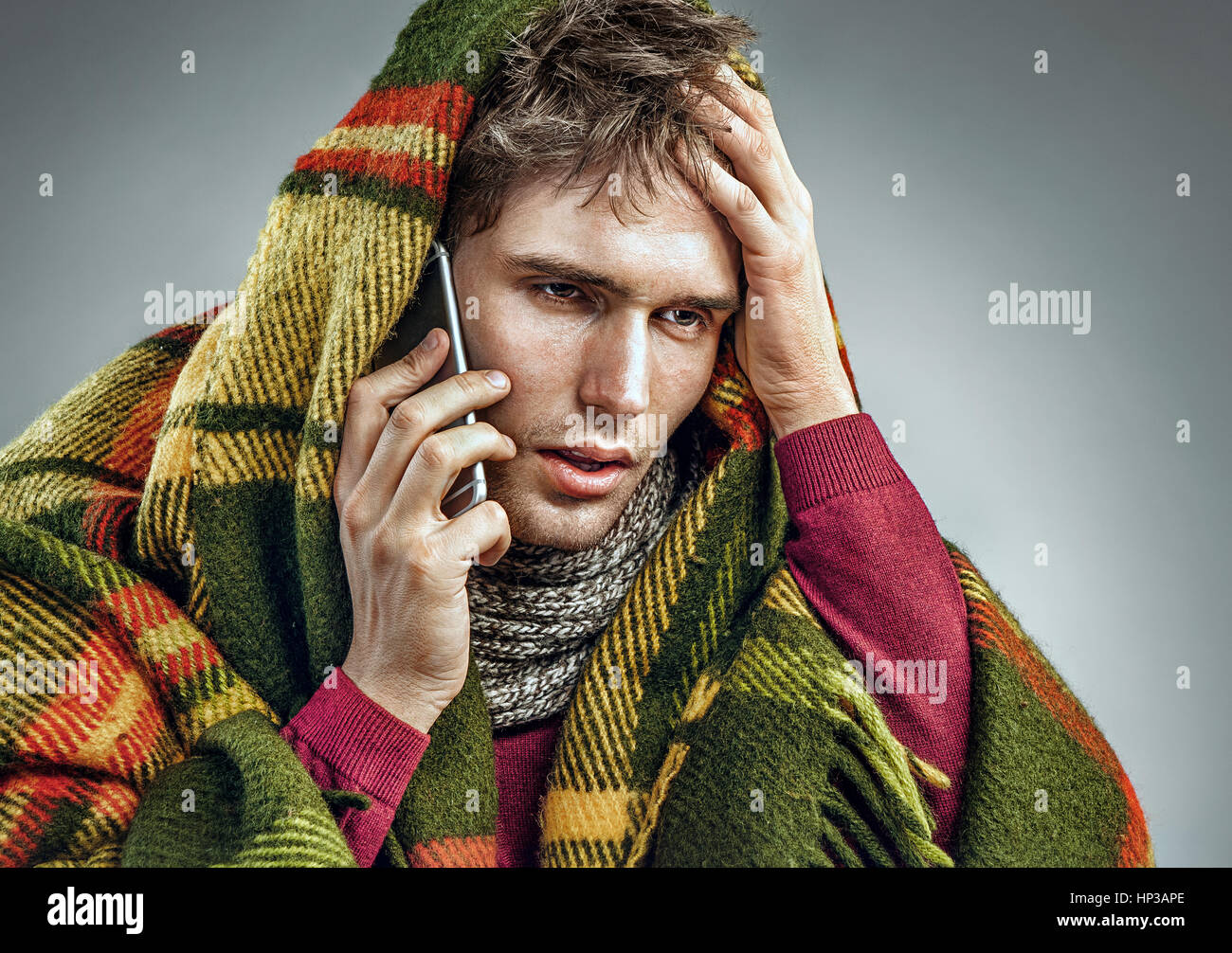 Unhealthy man wrapped in blanket with high temperature calling on the