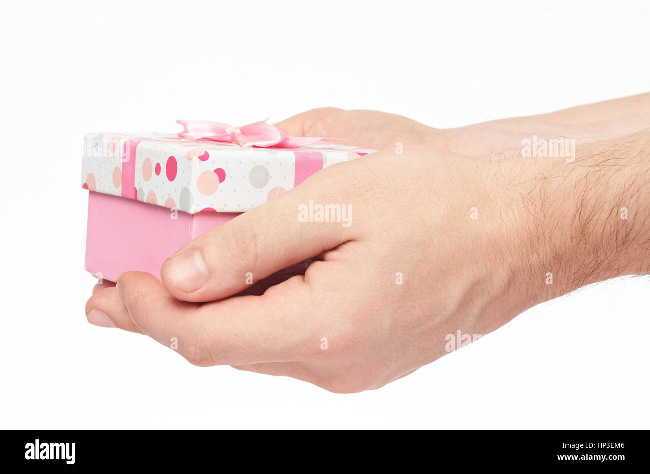 Holding pink gift box in hand isolated on white. Closeup of hand holding present pink box Stock Photo