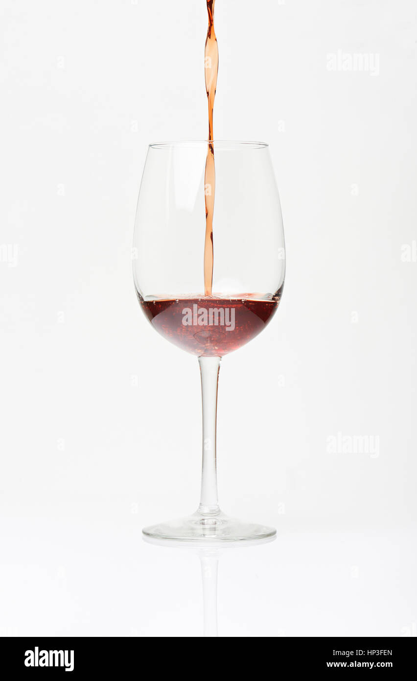 Pouring red wine in to glass. Glass half full with red wine. Vertical