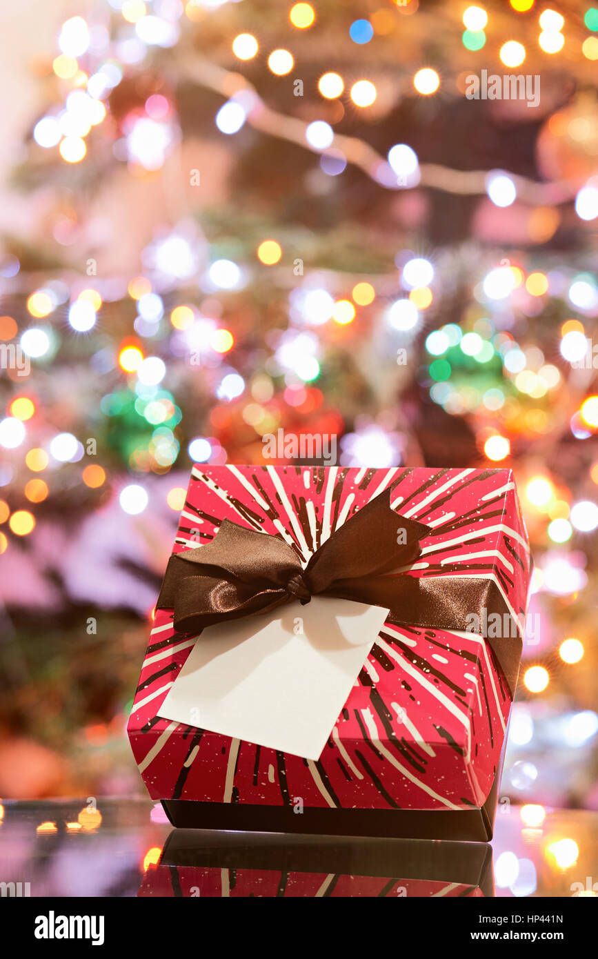 Gift strped box with brown bow for christmas on blurred light background Stock Photo