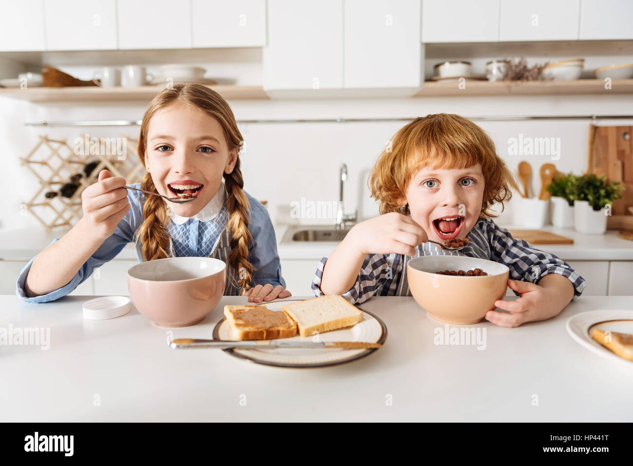 Bright positive children enjoying tasty chocolate flavored breakfast Stock Photo