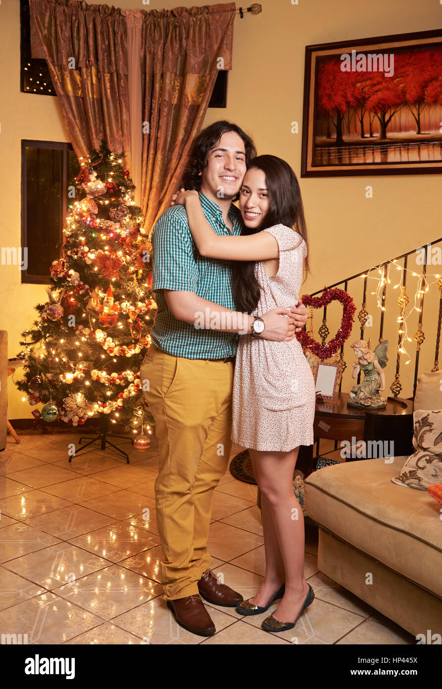 hugging young couple standing in house with christnas tree Stock Photo
