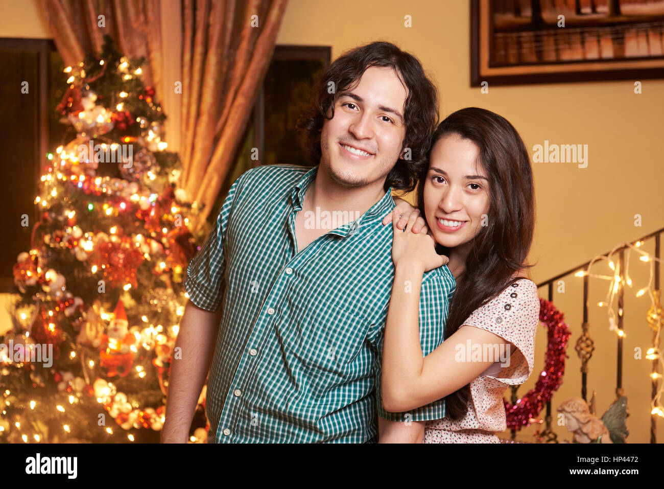 Smiling young couple with christmas tree decoration indoors Stock Photo