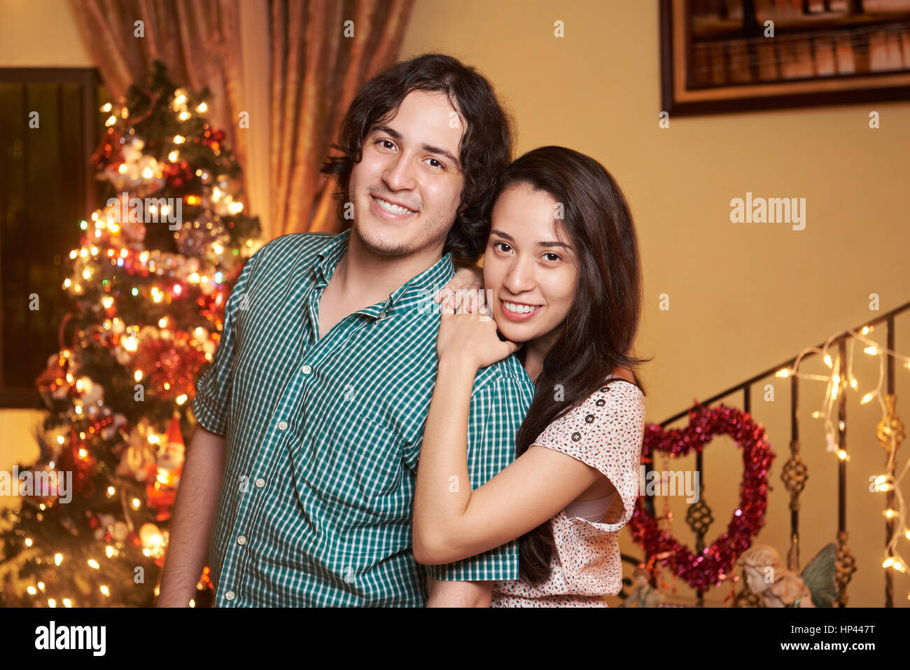 pretty hispanic couple in love  christmas evening. Married couple with christmas tree Stock Photo