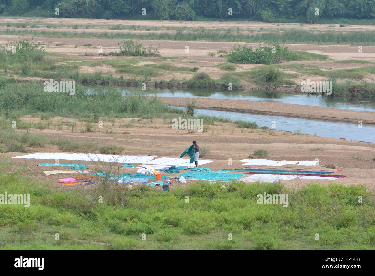 Near Mumbai, India - October 31, 2015 - Man drying clothes on river bank Stock Photo