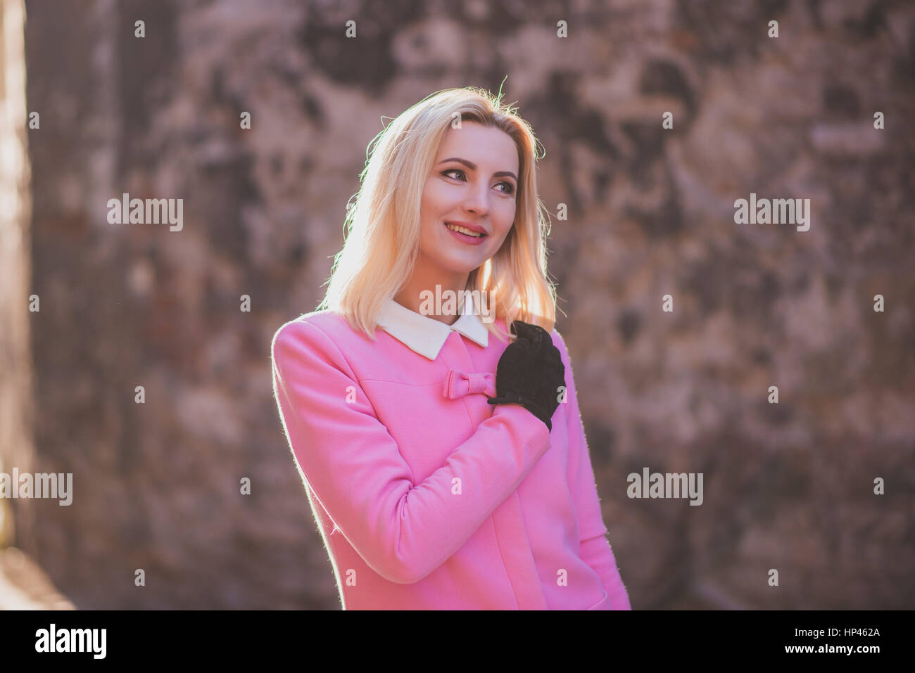 Attractive blonde lady touching hair with glove Stock Photo