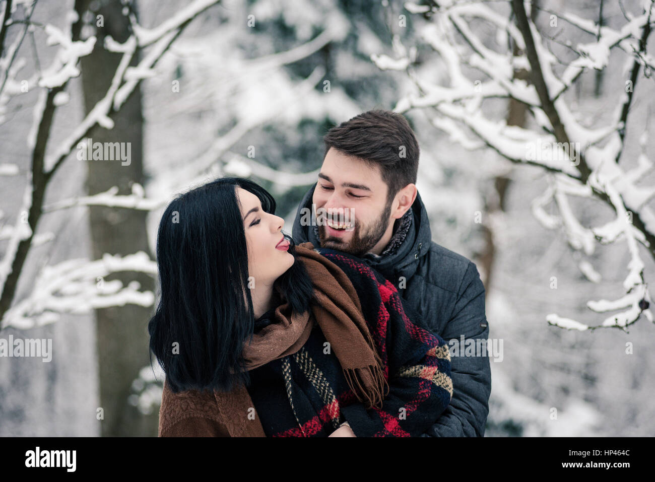 Happy couple hugging and fooling around in the snowy forest Stock Photo