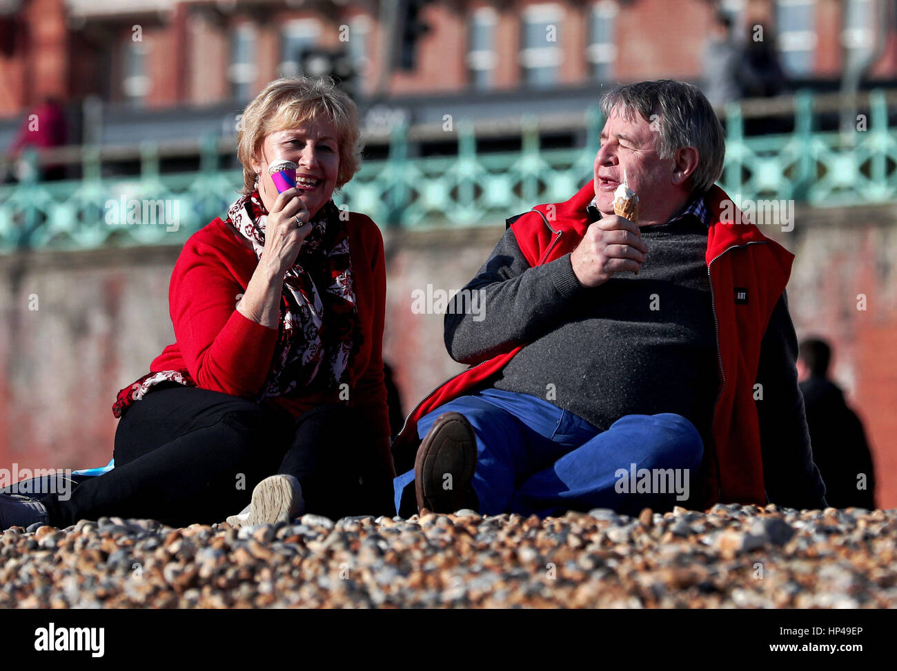 A couple enjoy the sunshine on the beach in Brighton, East Sussex. Stock Photo