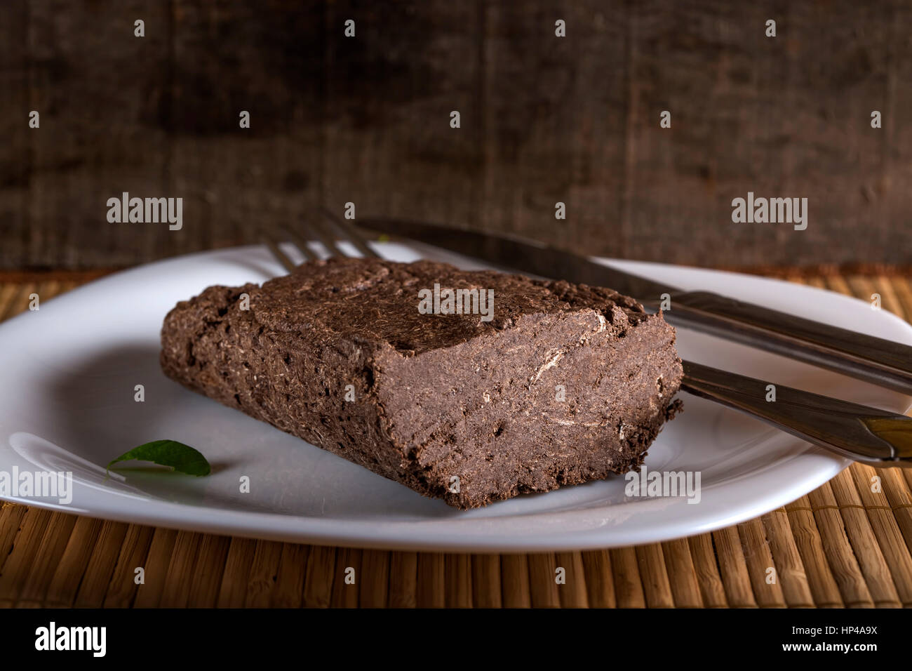 Halvah on white plate with knife and fork on wooden backgroun Stock Photo