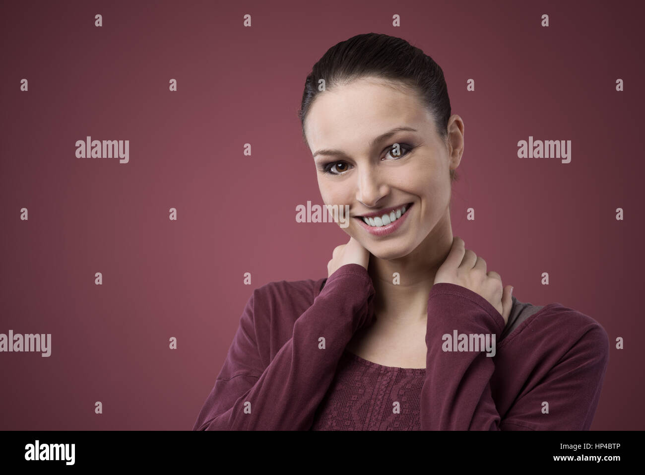 Smiling woman touching her shoulders and looking at camera Stock Photo ...