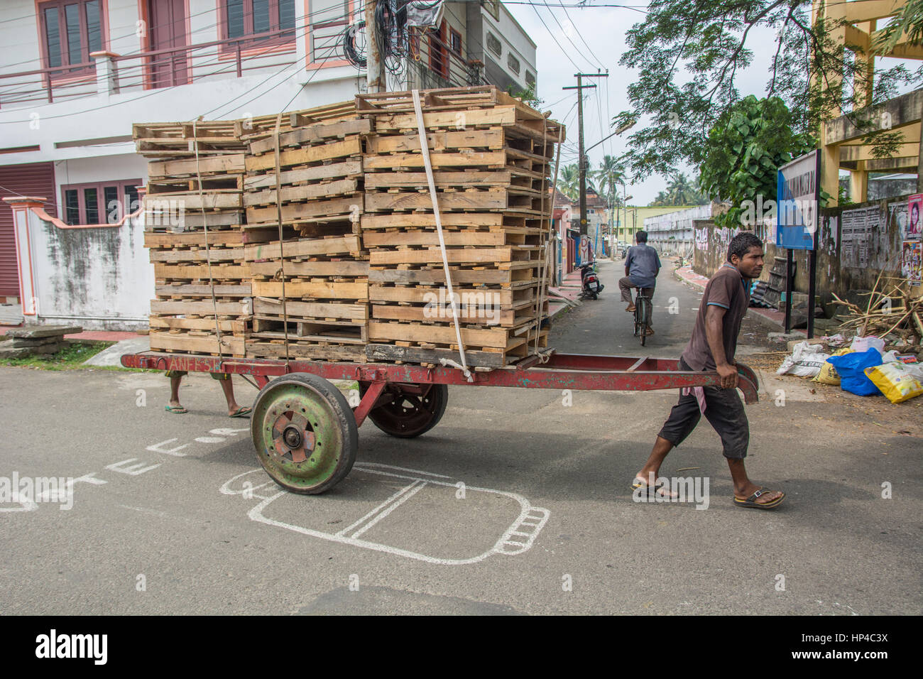 Mumbai, India - December 11, 2016 - Man pulling a cart with pallets slowly in the very crowded streets and traffic in Mumbai with tuk tuk and taxis Stock Photo