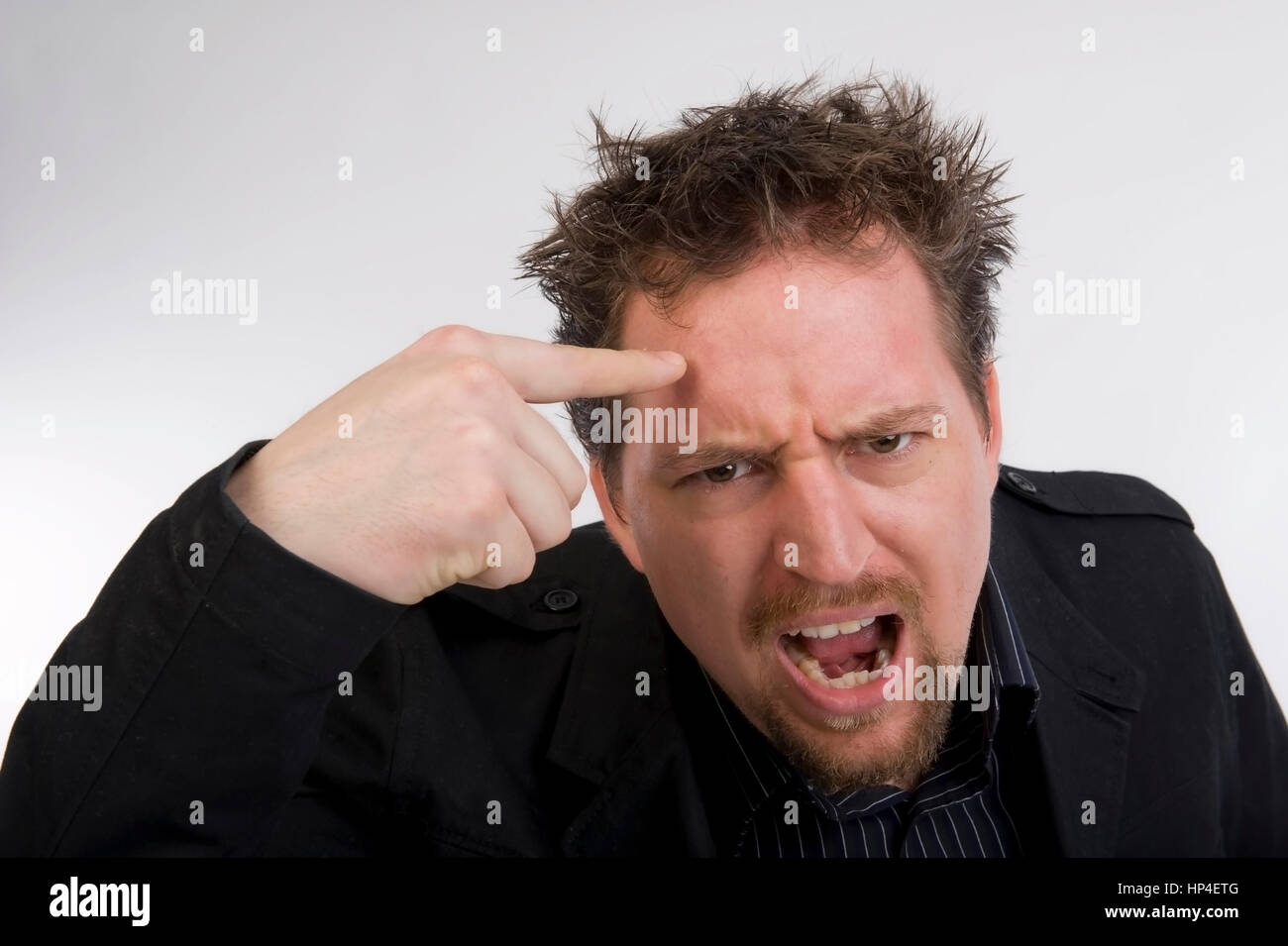 Model released , Zorniger, junger Mann zeigt den Vogel - young man  tap one's forehead Stock Photo