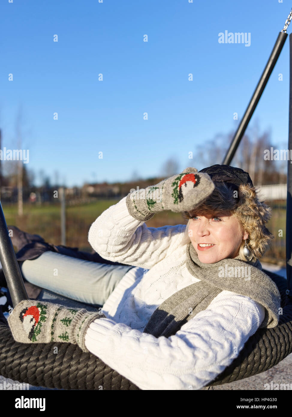 Park, mature woman sits in a swing, sunny winter day Stock Photo - Alamy