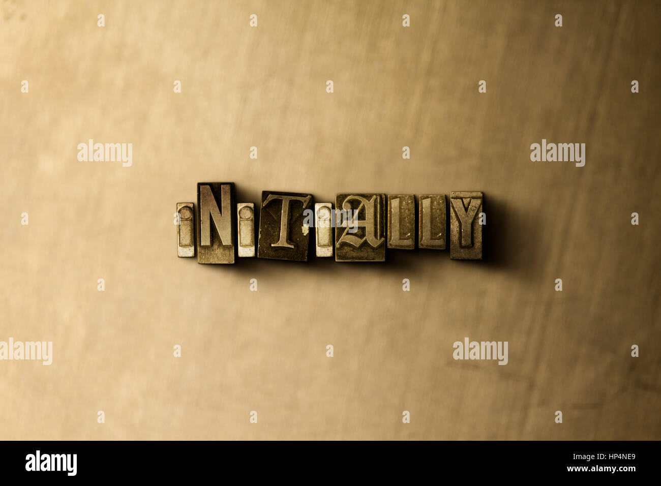 INITIALLY - close-up of grungy vintage typeset word on metal backdrop ...