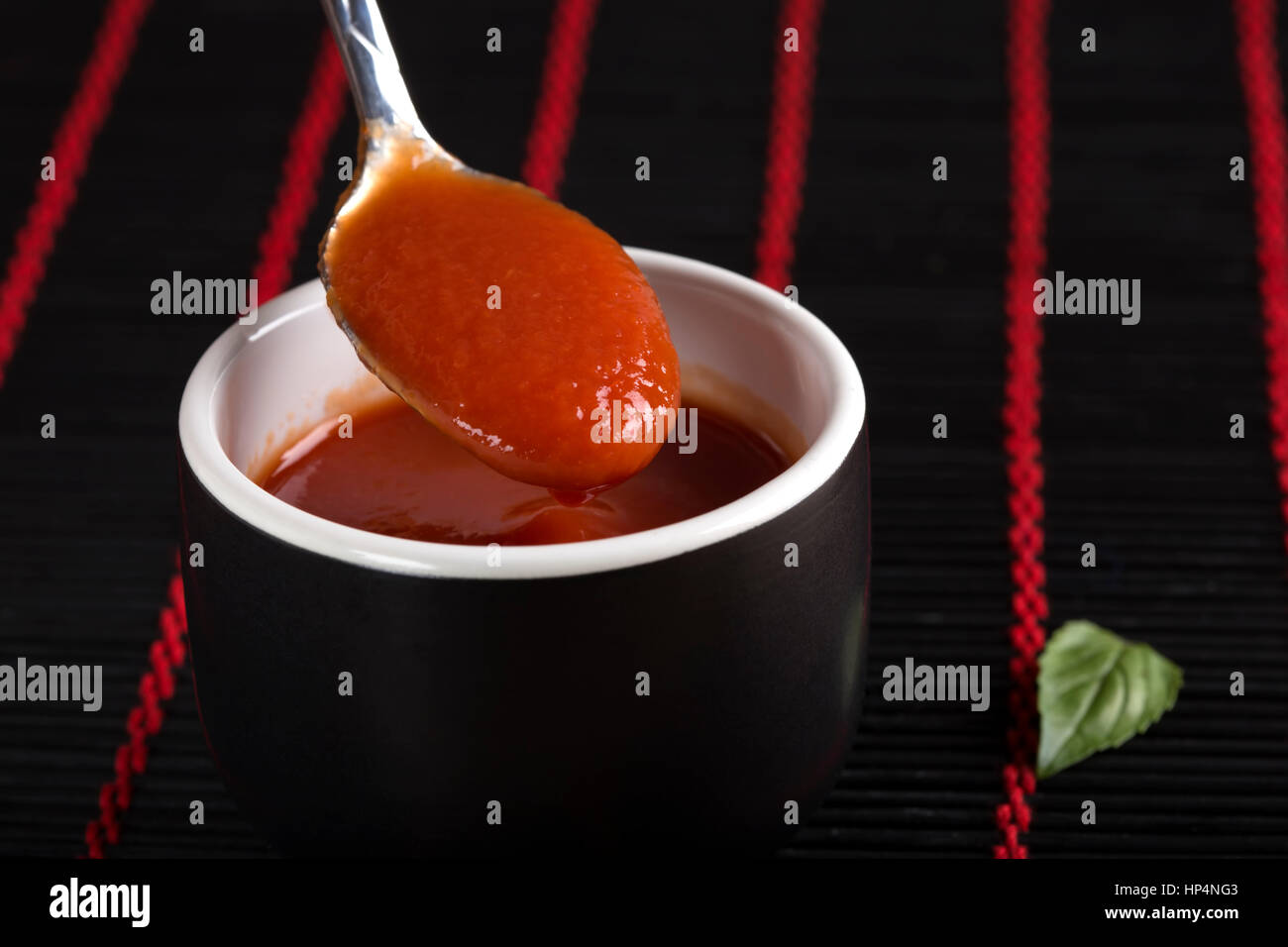 Teaspoon with fresh homemade tomato sauce over dark background Stock Photo