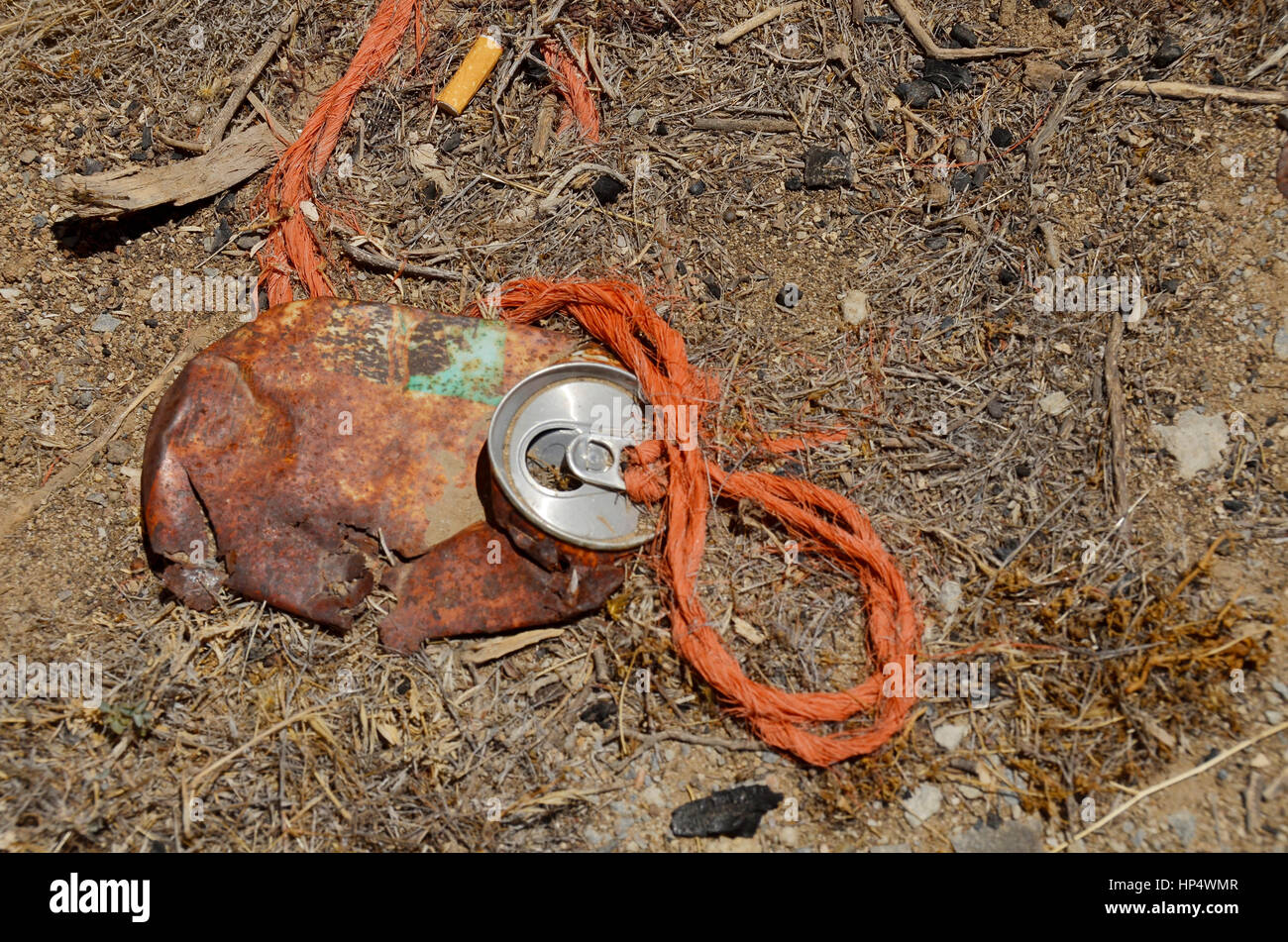 Abandoned, old flattened soda drink can with orange string attached Stock Photo