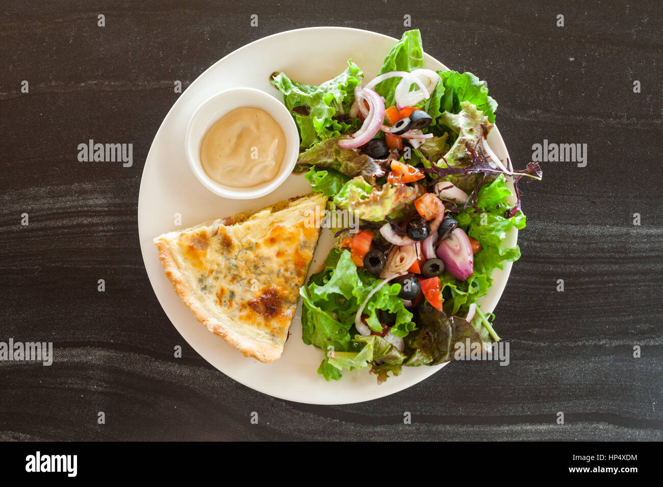 Quiche Lorraine with dijon mustard and salad on a slate table Stock