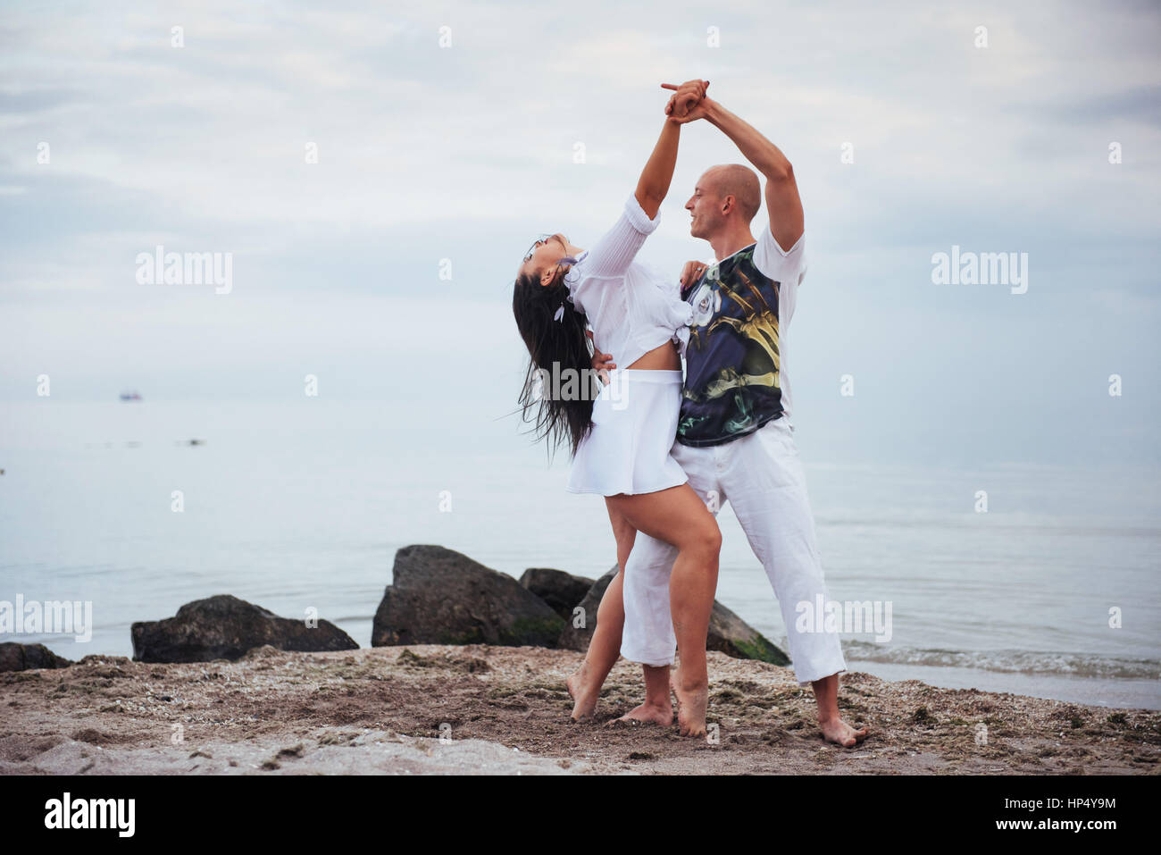 beautiful couple dancing on the beach at the background Stock Photo - Alamy
