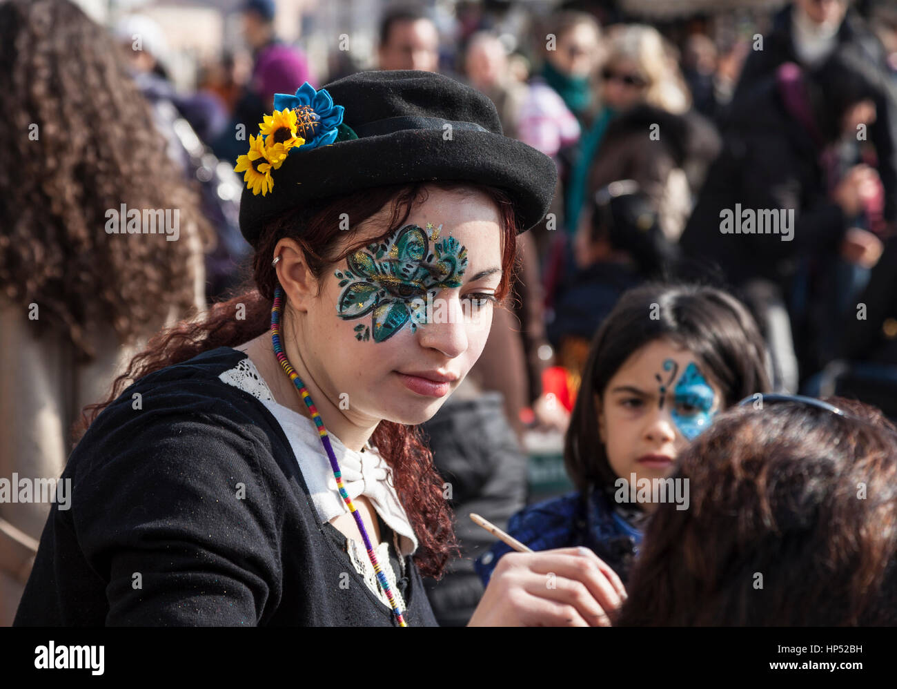 Venice,Italy-February 26, 2011: Environmental portrait of a female street face painter working on Sestiere Castello in Venice during the Venice carniv Stock Photo