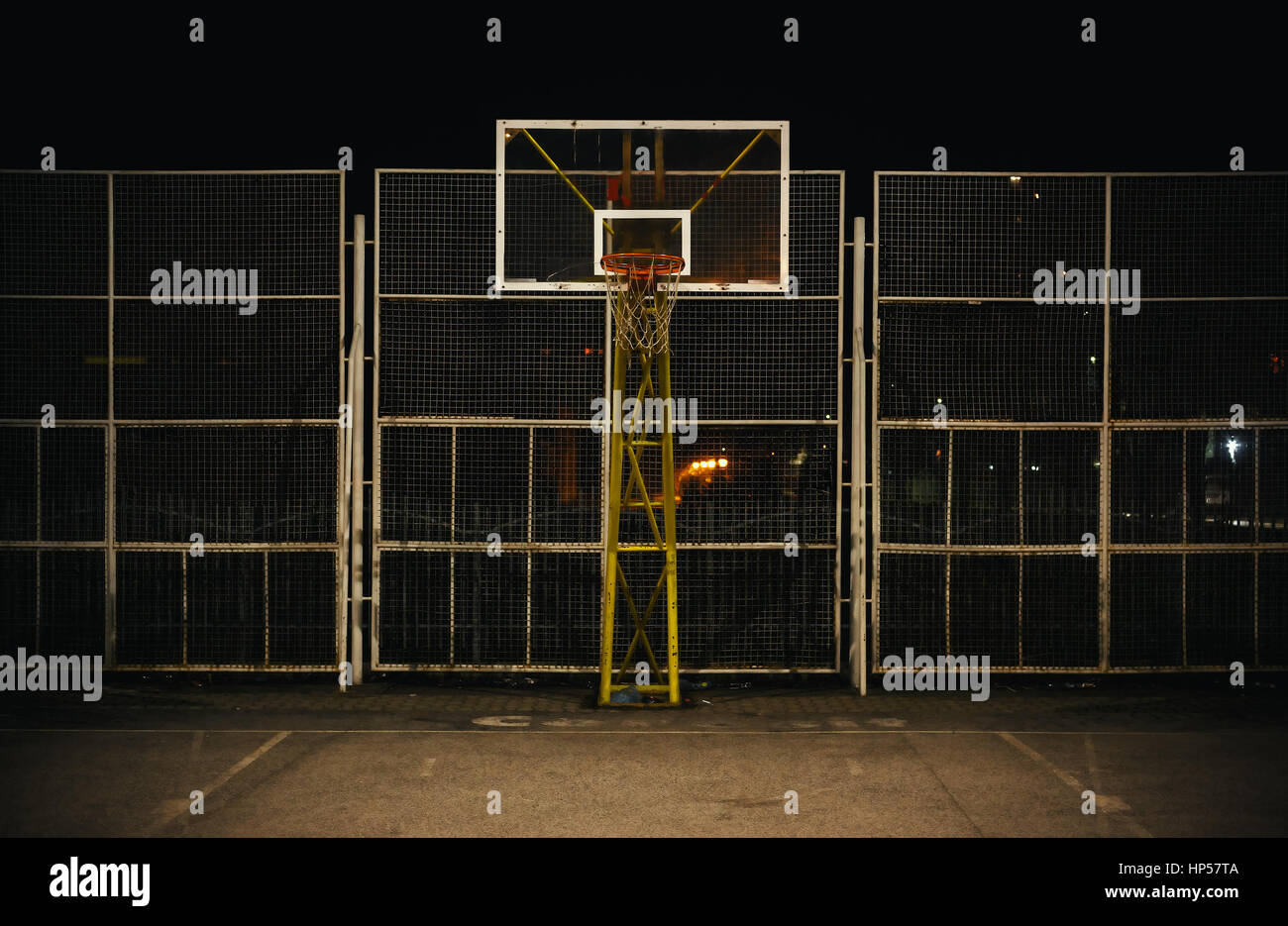 The basketball court during night, view on basketball hoop and fence