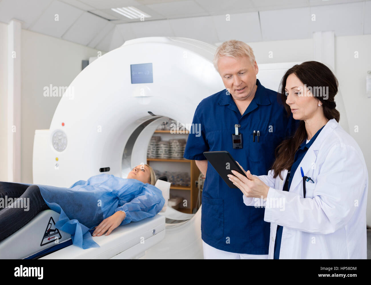 Colleagues Discussing Over Digital Tablet While Patient Undergoi Stock Photo