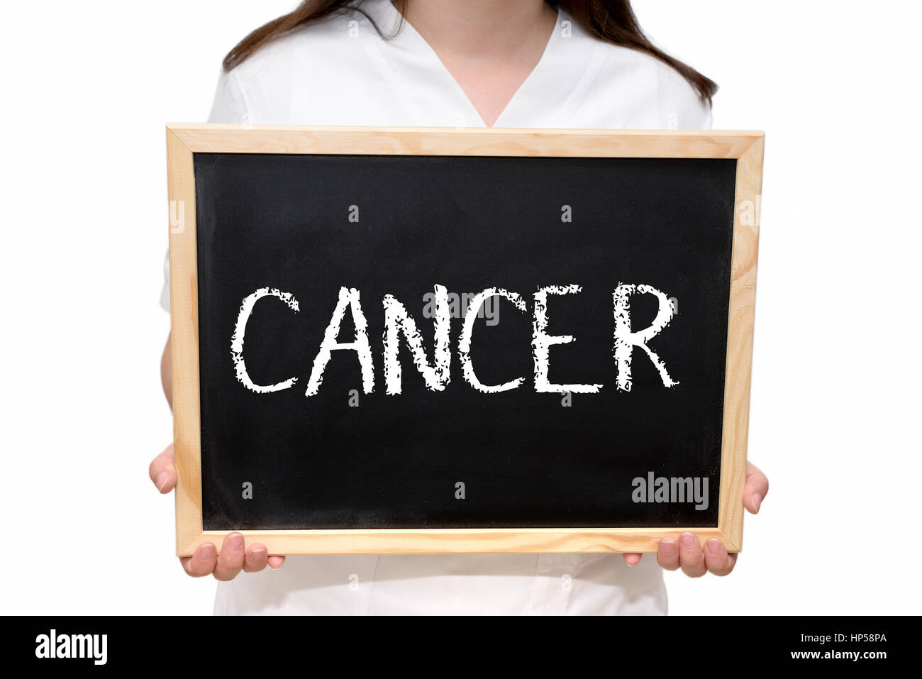 Female nurse holding a slate board with the text Cancer written with chalk, isolated on white background. Stock Photo