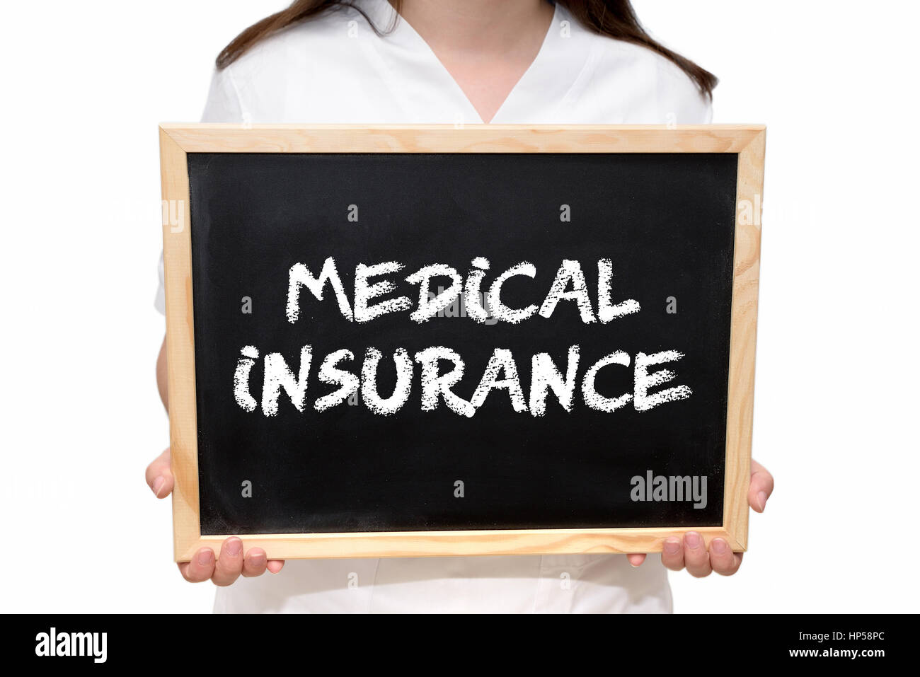 Female nurse holding a slate board with the text Medical Insurance written with chalk, isolated on white background. Stock Photo
