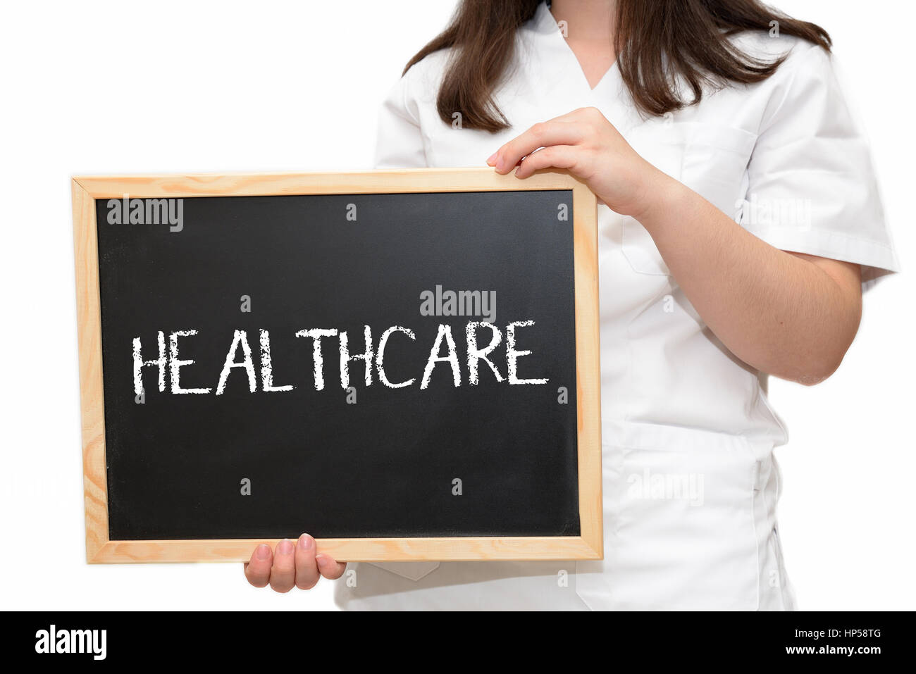 Female nurse holding a slate board with the text Healthcare written with chalk, isolated on white background. Stock Photo