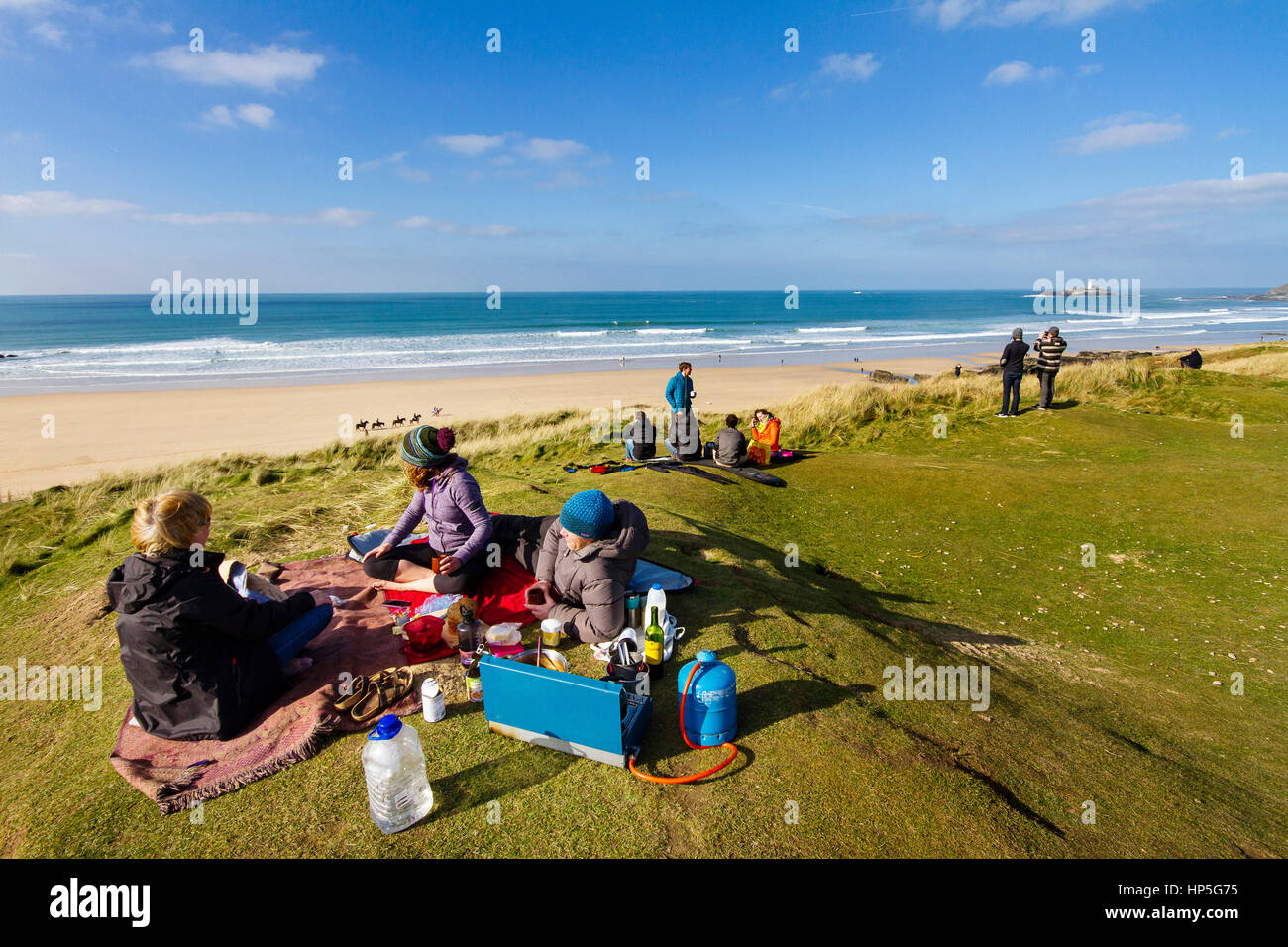 A family picnics on a cliff top in the sun after a surf in the briny. Stock Photo