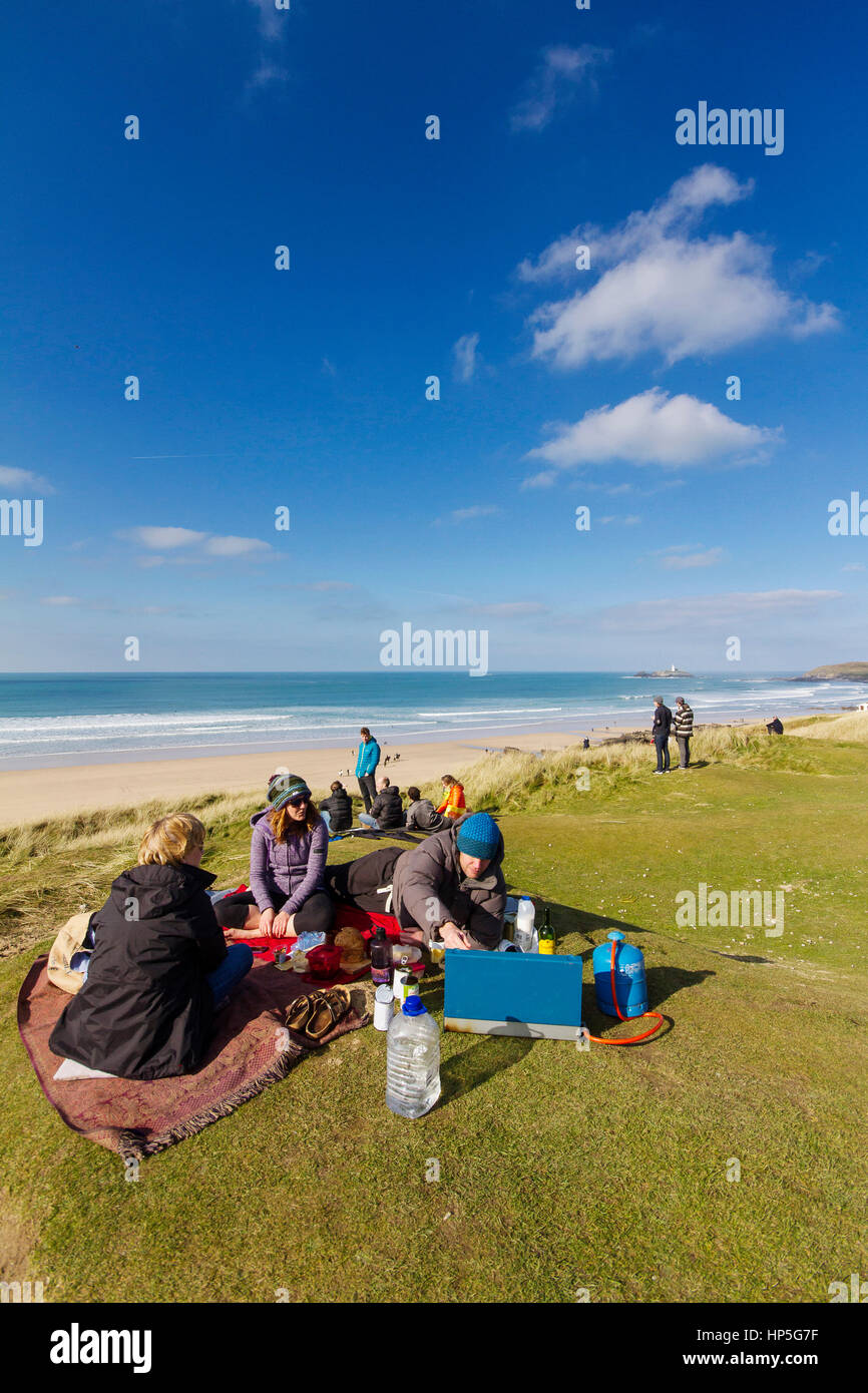 A family picnics on a cliff top in the sun after a surf in the briny