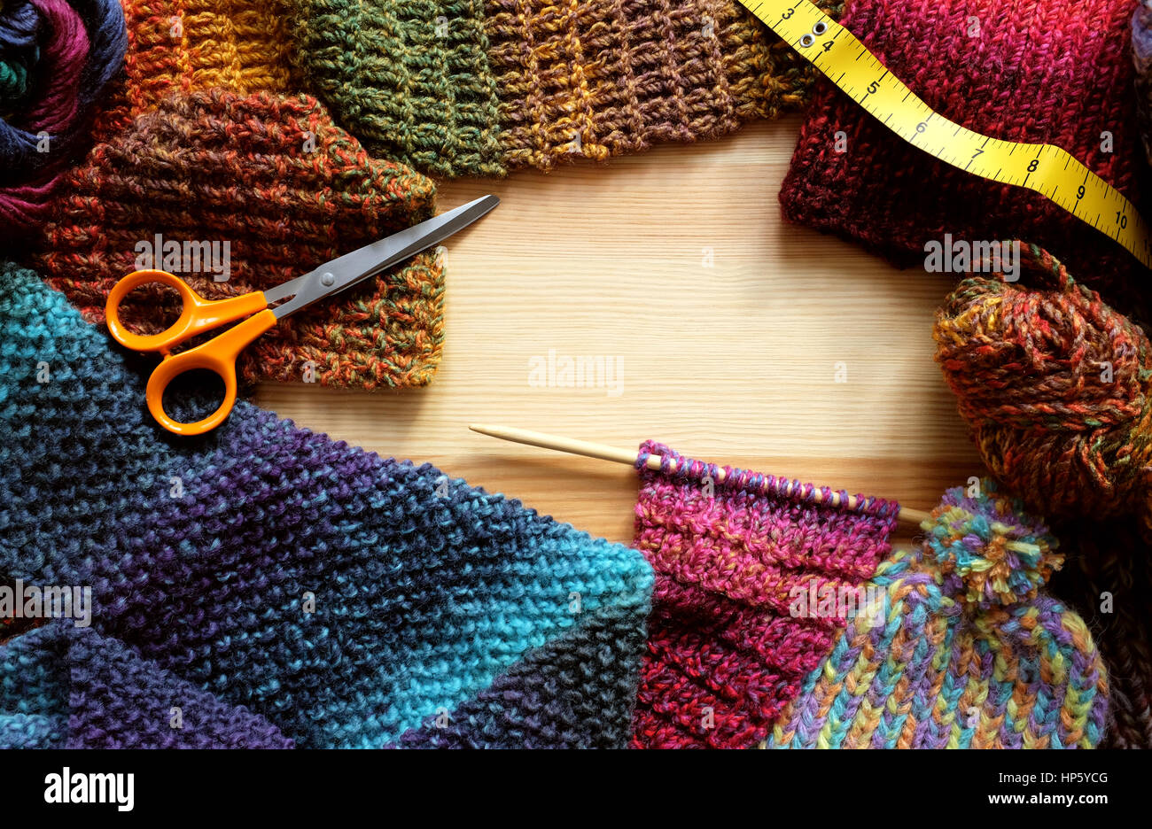 Border of knitting on needle, knitwear, wool, craft scissors and tape measure with copy space on wooden background Stock Photo