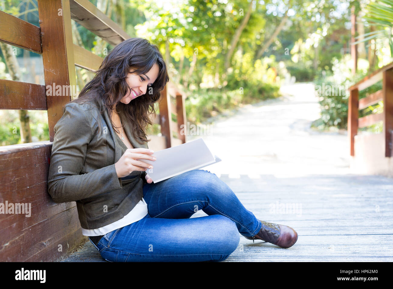 Young woman reading a book and relaxing at the park Stock Photo - Alamy