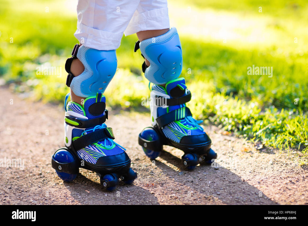 Girl and boy learn to roller skate in summer park. Children wearing  protection pads and safety helmet for safe skating Stock Photo - Alamy