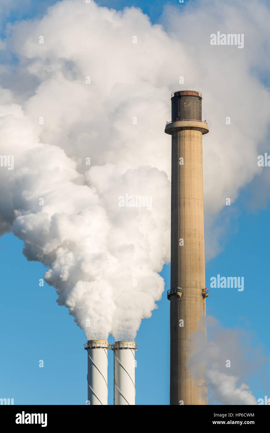 The pipes of a coal power plant with white smoke as a global warming concept. Stock Photo